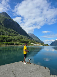 Rear view of woman standing by lake against sky