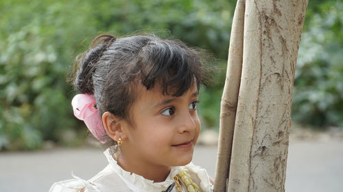 Close-up of cute girl by tree trunk
