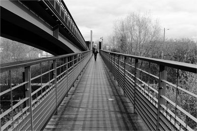 Rear view of woman walking on footbridge