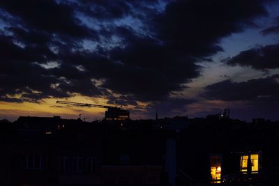 Silhouette of city against dramatic sky at sunset