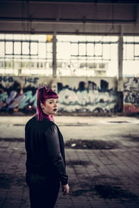 Portrait of young woman standing in abandoned building