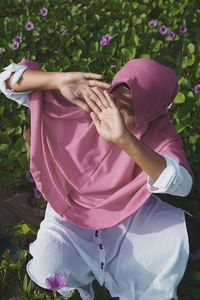 Midsection of woman standing by pink flowering plants