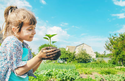 Smiling girl holding mud with plant