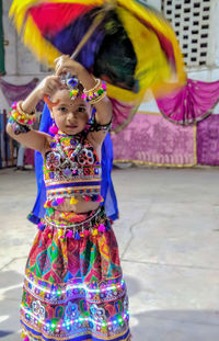 Portrait of girl in traditional clothing with umbrella standing on floor