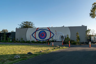 Graffiti on wall by road against clear blue sky