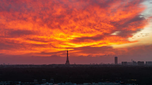 Silhouette eiffel tower against cloudy sky at sunset