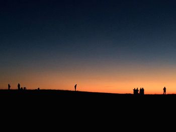 Silhouette people on mountain against clear sky at dusk