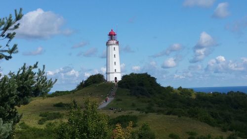 Lighthouse by sea against sky