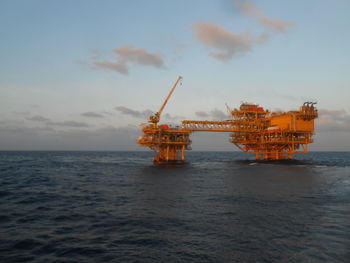 Traditional windmill in sea against sky
