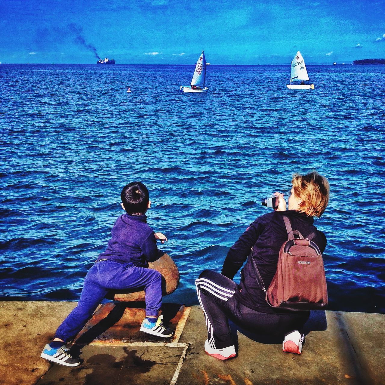 water, lifestyles, sea, leisure activity, blue, nautical vessel, rear view, men, transportation, sitting, full length, mode of transport, horizon over water, tranquility, scenics, beauty in nature, tranquil scene, boat