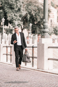 Urban businessman wearing jacket and shoulder bag. handsome male model in his 45s. 