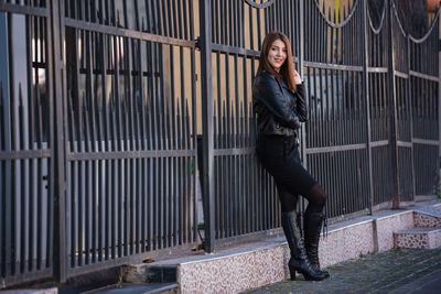 Full length portrait of woman standing against brick wall