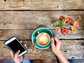 Cropped image of woman holding coffee cup on table