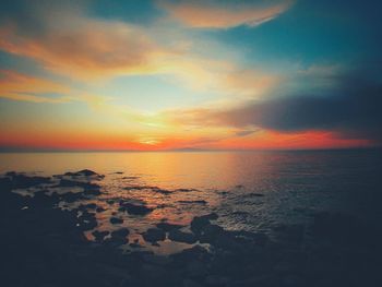 Scenic view of sea against dramatic sky during sunset