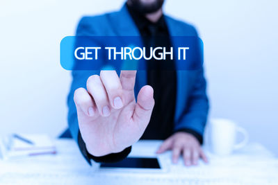 Midsection of man using smart phone against white background