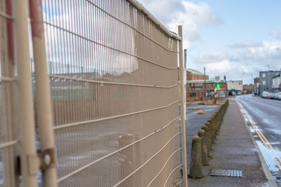 Road by fence against sky