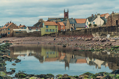 Buildings by river against sky in town