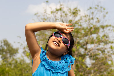 Portrait of young woman wearing sunglasses against trees