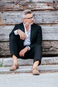 Businessman sitting against wooden wall