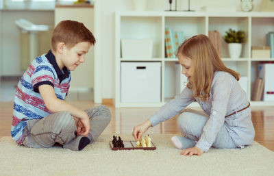 Full length of siblings playing at home