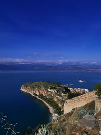 High angle view of city by sea against blue sky