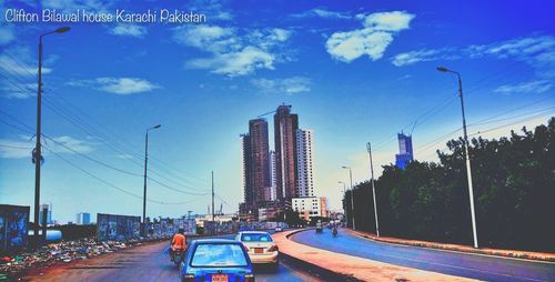 Cars on road in city against blue sky