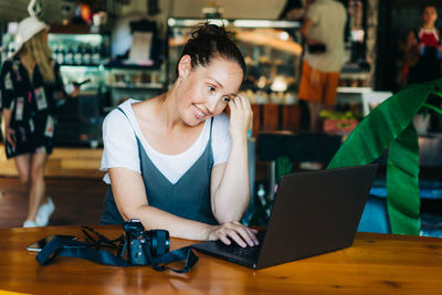 Woman using mobile phone while sitting on table