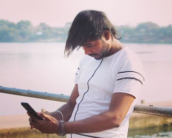 Young man using mobile phone in water