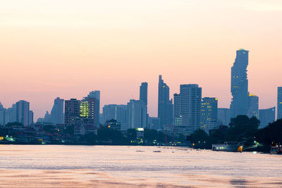 Modern buildings in city against sky during sunset