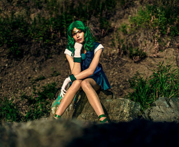 Portrait of young woman sitting on rock