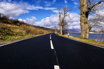 Road amidst bare trees against sky