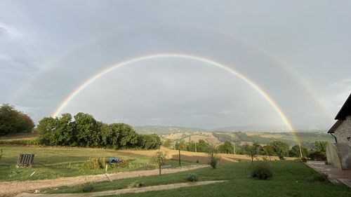 Scenic view of rainbow over field against sky