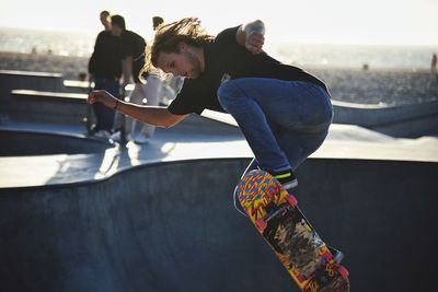 Full length of young man skateboarding at park against sky