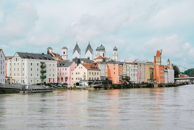 View of buildings at waterfront against cloudy sky