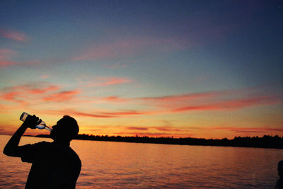 Silhouette woman photographing at sunset