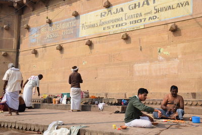 Group of people sitting against wall