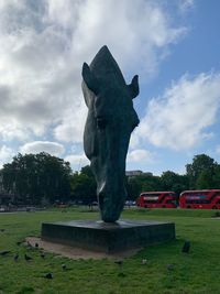 Statue on field in park against sky