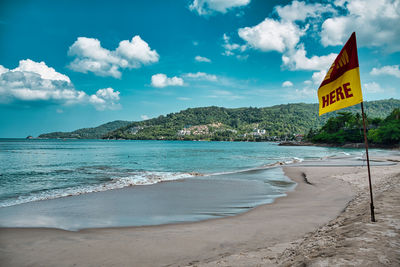 Empty, calm sandy patong beach in phuket with turquoise blue clear water and cirrus cloudy sky