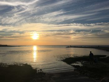 Silhouette man on beach against sky during sunset