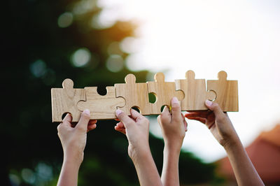 Cropped hands of woman holding jigsaw pieces on table