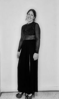 Portrait of a smiling young woman standing against wall