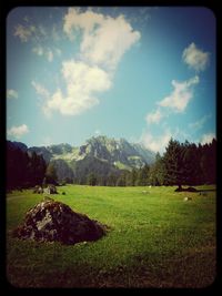 Scenic view of grassy field against cloudy sky