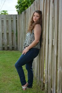 Portrait of young woman standing by fence