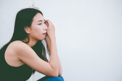 Beautiful young woman looking away against white background