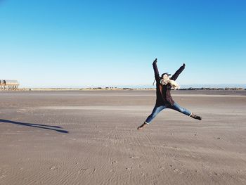 Woman jumping outdoors against clear blue sky
