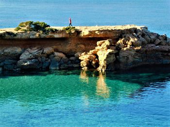 Man standing on rock by sea