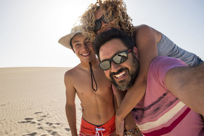 Portrait of happy family standing on sand at desert