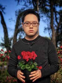 Portrait of young man standing by flowering plants