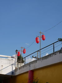 Low angle view of red lanterns hanging against clear blue sky