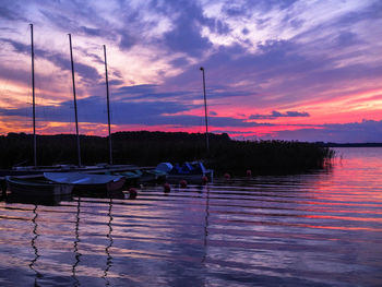 Sailboats moored in lake against sky during sunset